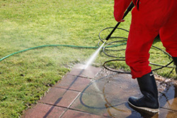 Handyman using a pressure washer on patio tiles